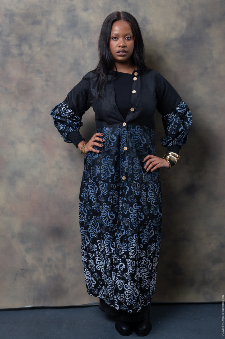 The model is wearing wearing a black and silver-blue kimono with intricate swirling patterns, featuring voluminous sleeves and silver-blue detailing.